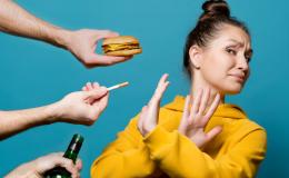 Kobieta odwraca głowę i krzyżuje ręce na znak protestu przed papierosem, fast foodem i alkoholem.