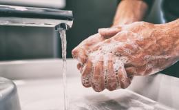 Namydlone dłonie mężczyny nad umywalką podczas mycia rąk.