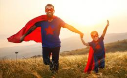ojciec i syn na łące w czerwonych pelerynach