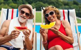 Mężczyzna i kobieta na leżakach, nad basenem. W strojach kąpielowych i okularach przeciwsłownecznych. Jedzą arbuzy. 