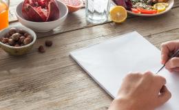 ręce z kartką i długopisem na stole z produktami żywieniowymi