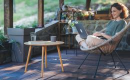 Kobieta na werandzie w wiklinowym fotelu z laptopem