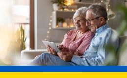 Starsza para na kanapie patrzy na tablet ukr