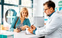 pacjentka z telefonem w aptece rozmawia z farmaceutą