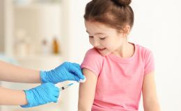 Widać ręce pielęgniarki i szczepioną kilkuletnią dziewczynke