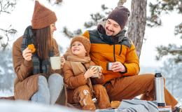 rodzinka w zimowym lesie pije herbatę z termosu