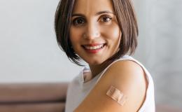 uśmiechnięta kobieta z plastrem na lewym ramieniu