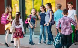 Grupa dzieci wita się przed szkołą