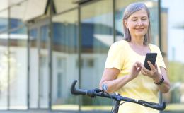 Kobieta przed biurowcem sprawdza coś w komorce