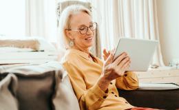 Starsza pani w żółtej bluzce z tabletem