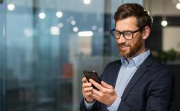 młody brodaty facet z komórką przed bankiem