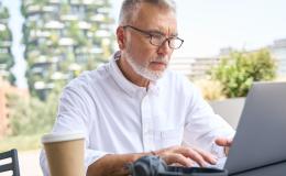 mężczyzna z brodą w białej koszuli przy komputerze