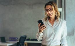 Dzewczyna w bialej  bluzce z komórką , w tle  biuro