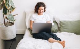 Kobieta siedzaca na łozku z laptopem