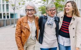 trzy panie w roznym wieku ida ulica rozesmiane i objete 