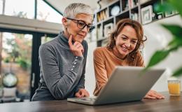 dwie panie nad laptopem, jedna ma siwe włosy