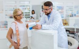 farmaceuta tłumaczy coś starszej pacjentce z lekiem w ręku