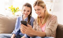 matka z komórką w ręku z córka na kanapie