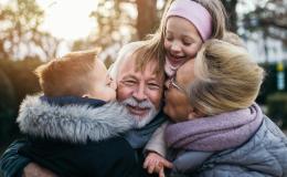 Dziadek, babcia, sciskające go wnuki