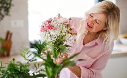 Kobieta wstawia kwiaty do wazonu