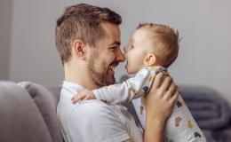 Tata z małym dzieckiem, trzyma je w ramionach i patrzą na siebie