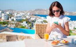 Kobieta z komórką, w tle greckie miasteczko