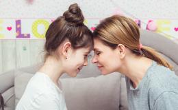 Matka i córka czule dotykają się czolami, nastolatka w koku, matka z rozpuszczonymi