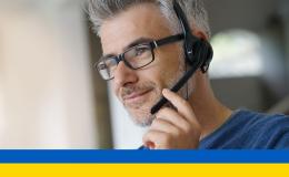 mężczyzna w słuchawkach na głowę, w okularach, siwe skroniie ukr flaga