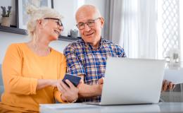 starsza pani z komórką, starszy an z laptopem, smieją się