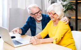 para starszych osób, Pan pokazuje z uśmiechem na treść na laptopie pani