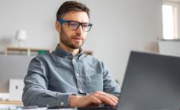 Młody mężczyzna w okularach przed laptopem