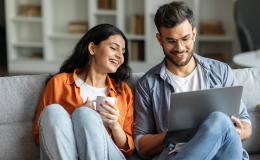 Para na kanapie, młodzi, zadowoleni, chlopak z laptopem