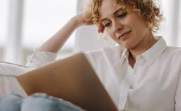 kobieta z laptopem na kolanach, w białej bluzce