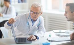 Lekarz pokazuje coś pacjentowi w komputerze