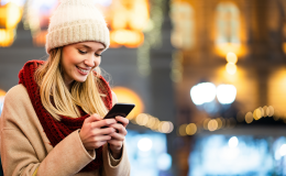 Kobieta z komórką, w czapce, w tle nocne miasto