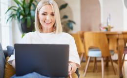 Kobieta w białym t-shircie z laptopem na kanapie