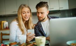 po sniadaniu w kuchni, cz\lopak przed laptopem patrzy na dziewczynę z komórką