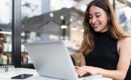 uśmiechnięta kobieta przed laptopem, ma długie włosy