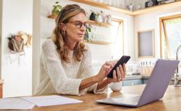 Pani patrz na telefon, a przed nią komputer. Jest poważna