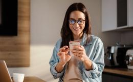 młoda szatynka z telefonem w swojej kuchni