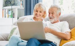 para w średnim wieku na kanapie z komputerem