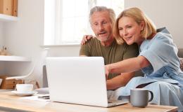 Para na kanapie patrzy w komputer