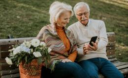 Starsza para na ławce, on pokazuje jej coś w telefonie