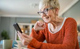 Starsza pani w czerwonej bluzce z telefonem w ręku