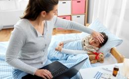 Matka sprawdza czolo córki i ma otwarty kompuer na kolanach