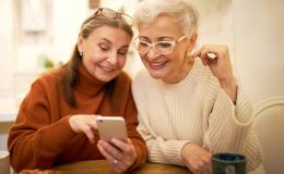 Dwie panie ok. 60 lat, jedna pokazuje drugiej coś w komórce