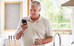 50latek w kuchni patrzy na telefon