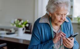 Starsza pani wybiera coś na komorce