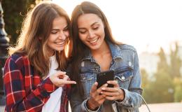 kobieta we flanelowej koszuli pokazuje drgiej coś na jej komórce