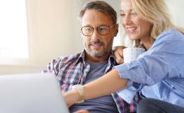 Kobieta z kubkiem kawy pokazuje coś na ekranie kompa mężczyźnie